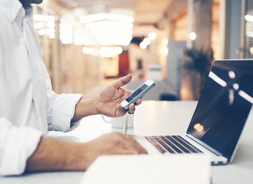 A man using a laptop and a smartphone